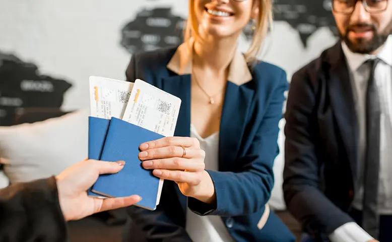 Couple Receiving Plane Tickets from Travel Agent in Office